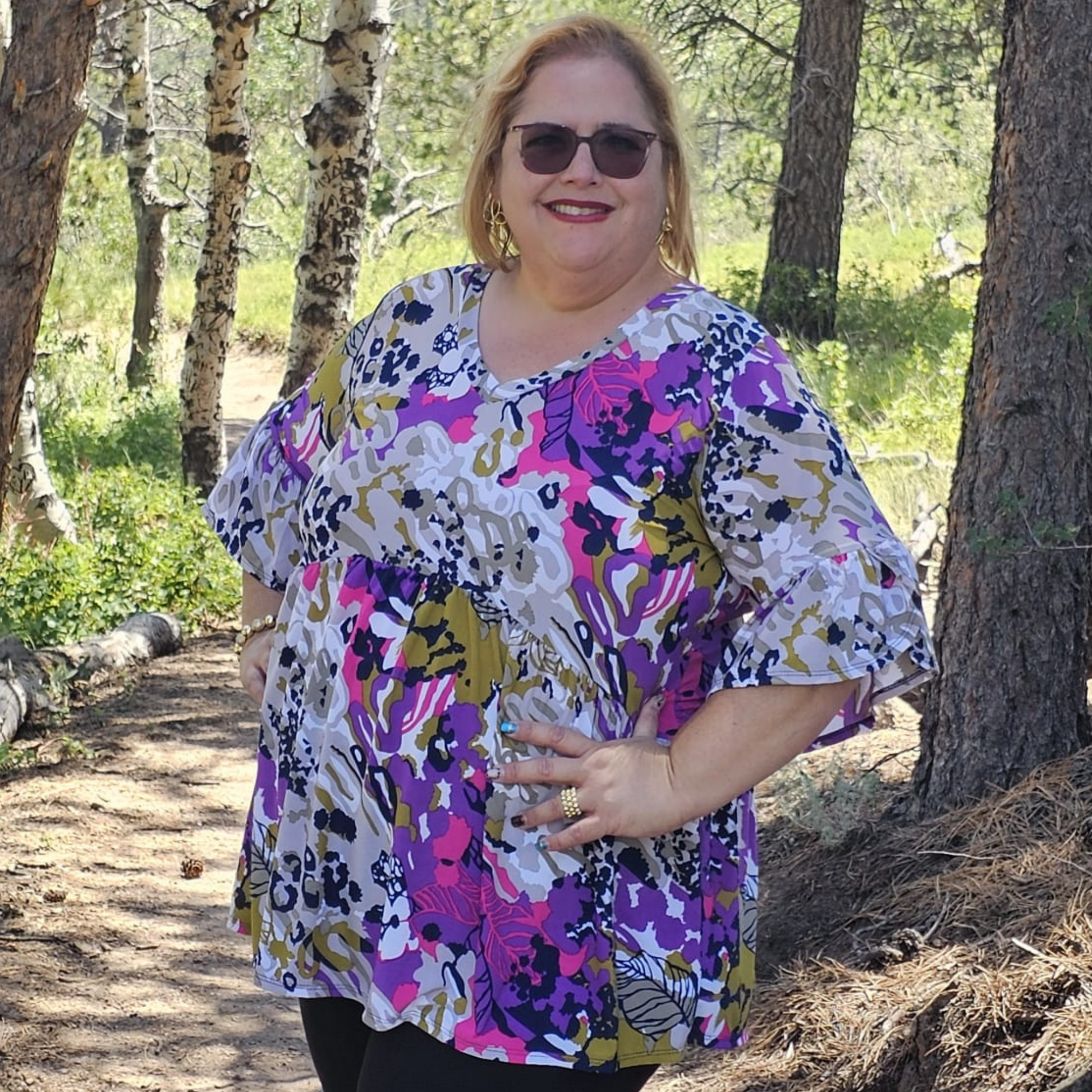 Blusa de mujer con estampado floral abstracto en tonos fucsia, púrpura, blanco y mostaza, mangas tres cuartos con vuelo y corte amplio tipo túnica.