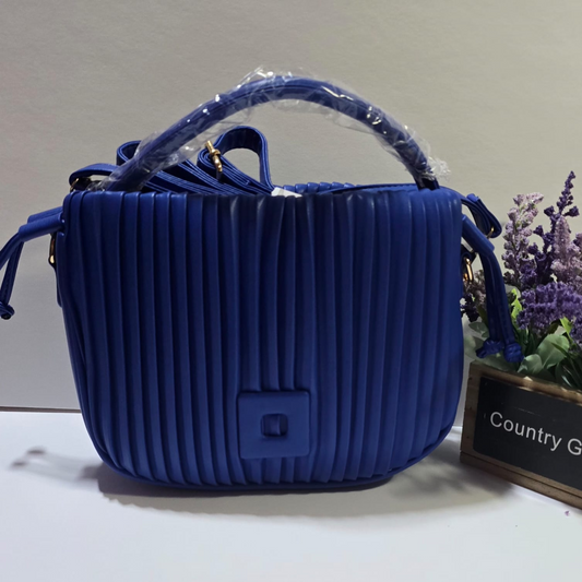 Bolso azul acolchado con textura de pliegues verticales y asa superior, estilo moderno y elegante

