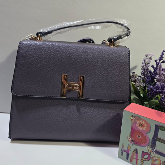 Cartera de cuero sintético color gris oscuro con hebilla dorada en forma de H y asa superior.