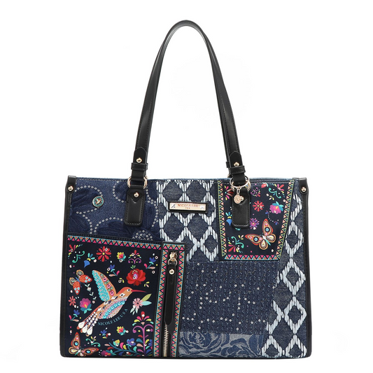 Cartera tote patchwork azul con estampados florales, mariposas y colibrí, asas negras y bolsillo frontal con cierre, marca Nicole Lee.
