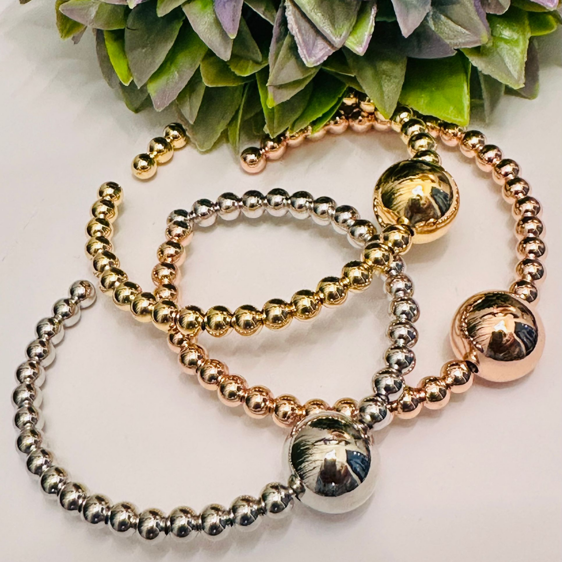 Pulsera de cuentas apilables para mujer con alambre de memoria, disponible en plata esterlina, oro rosa y oro amarillo vermeil, sobre fondo blanco.
