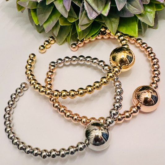 Pulsera de cuentas apilables para mujer con alambre de memoria, disponible en plata esterlina, oro rosa y oro amarillo vermeil, sobre fondo blanco.